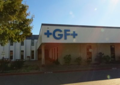 Picture of +GF+ blue channel letters mounted to side of building overhang.