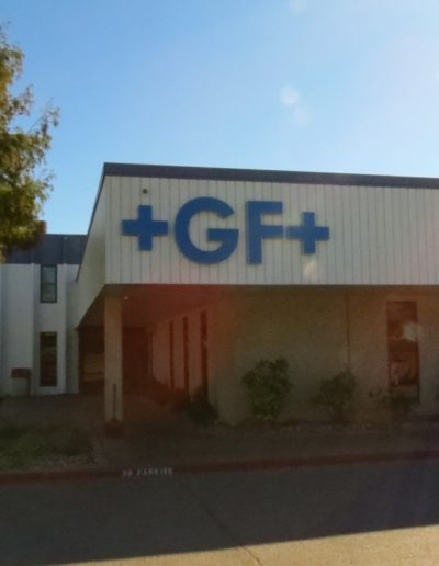 Picture of +GF+ blue channel letters mounted to side of building overhang.