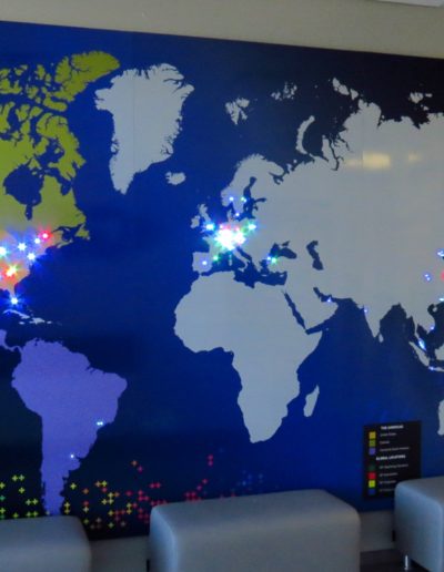 Photo of a large map of the world with different colored LED pin lights in various areas.