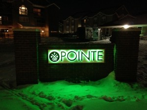 Sign design for The Pointe halo lit at night in the snow.