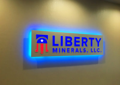 Picture of illuminated logo sign on wall with blue halo glow around perimeter.