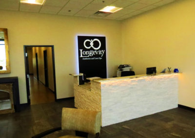Angled picture of illuminated monolith sign against wall behind reception desk.