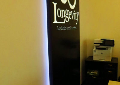 Side picture of wall sign with halo lighting around edges, black faced with white logo on front.