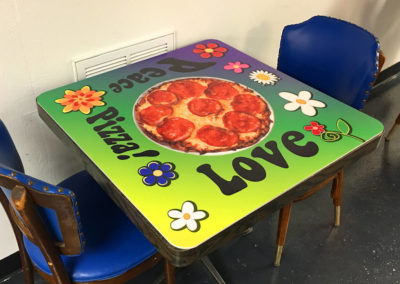 Picture of custom table top with Peace, Love, Pizza in colorful graphics.